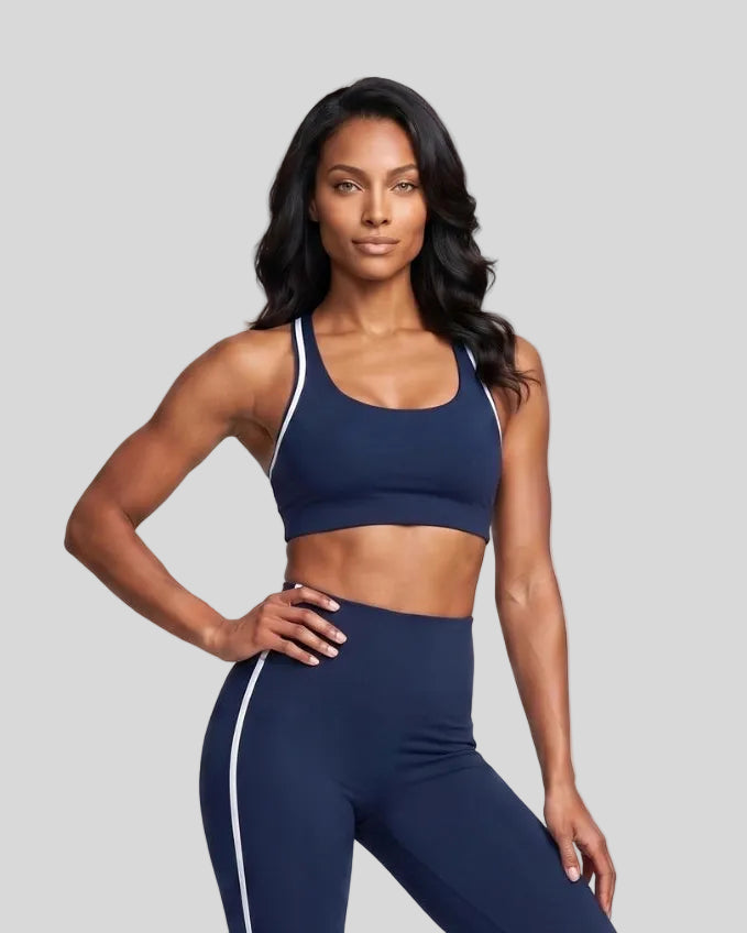 Model wearing the Athlesi TrackLine Edge Sports Bra in navy blue with white contrast trim, front view
