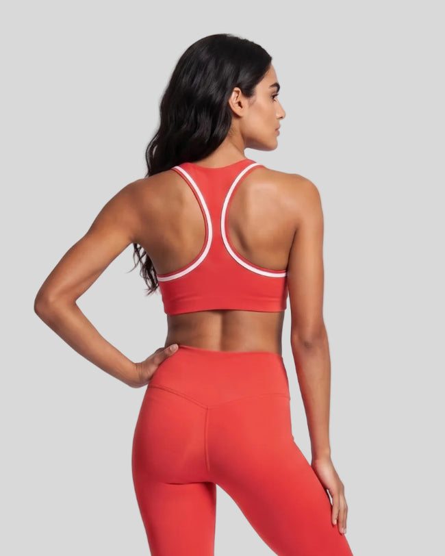 Model wearing the Athlesi TrackLine Edge Sports Bra in red with white contrast trim and racerback design, back view