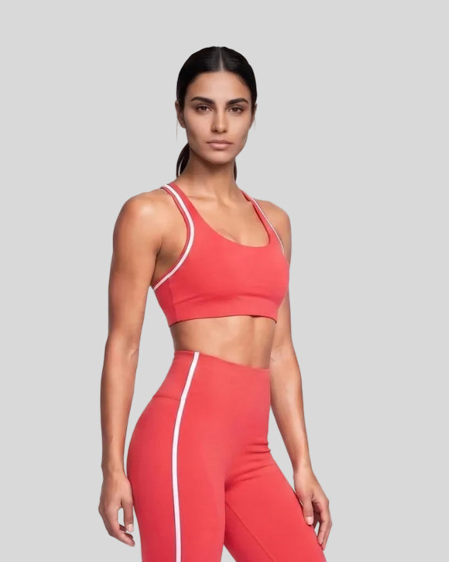 Model wearing the Athlesi TrackLine Edge Sports Bra in red with white contrast trim from a front angle