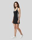 Full body front view of a woman wearing the Athlesi TrackLine Halter Dress in black