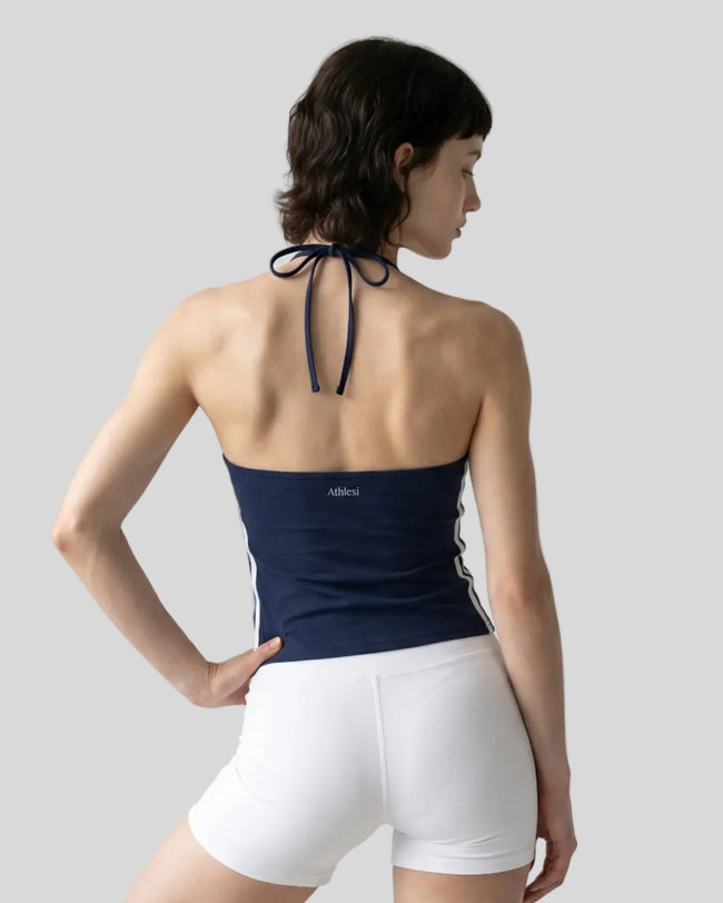 Back view of a woman wearing the Athlesi TrackLine Halter Tank in navy blue and white