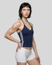 Front angle view of a woman wearing the Athlesi TrackLine Halter Tank in navy blue and white