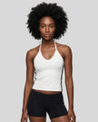 Mid body front view of a woman wearing the Athlesi TrackLine Halter Tank in white and black