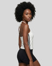 Side view of a woman wearing the Athlesi TrackLine Halter Tank in white and black
