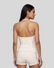 Mid body back view of woman wearing TrackLine Halter Yoga Top in apricot