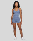 Full body front view of woman wearing blue TrackLine Halter Yoga Top with matching TrackLine Yoga Shorts