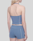 Mid body angled back view of woman wearing TrackLine Halter Yoga Top in blue