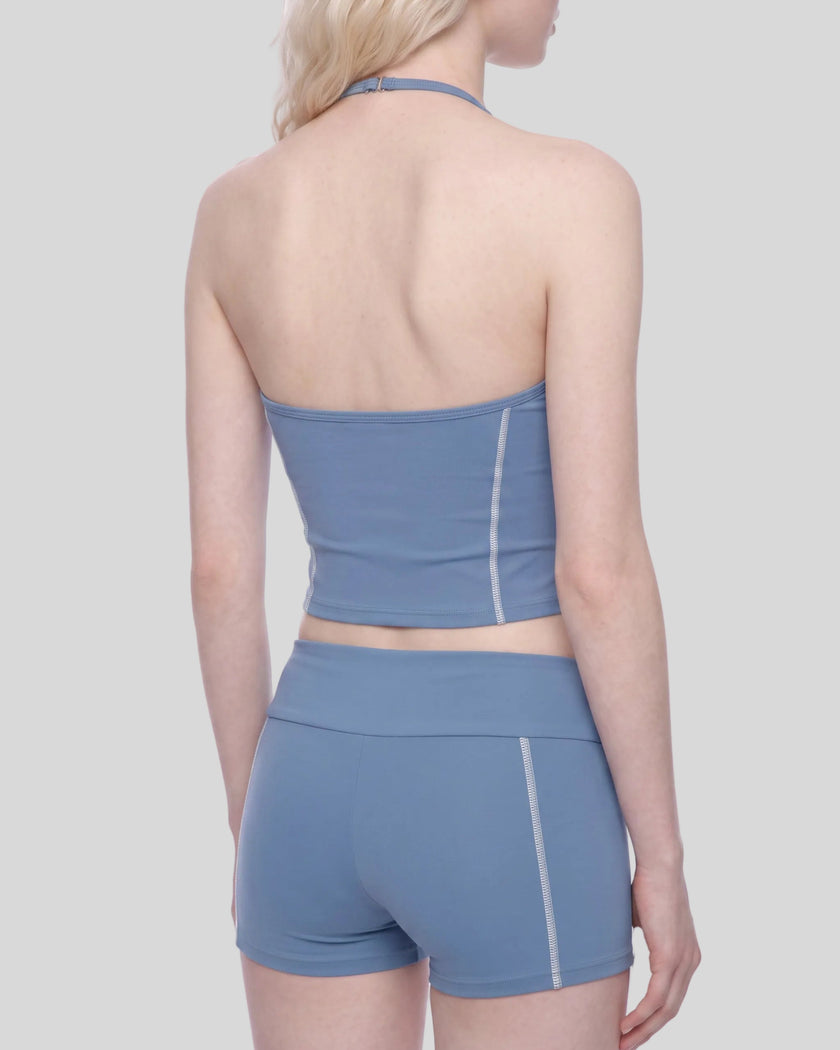 Mid body angled back view of woman wearing TrackLine Halter Yoga Top in blue