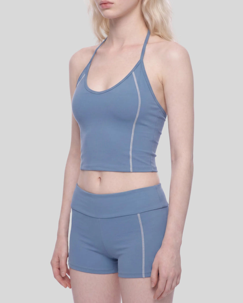 Mid body angled front view of woman wearing TrackLine Halter Yoga Top in blue