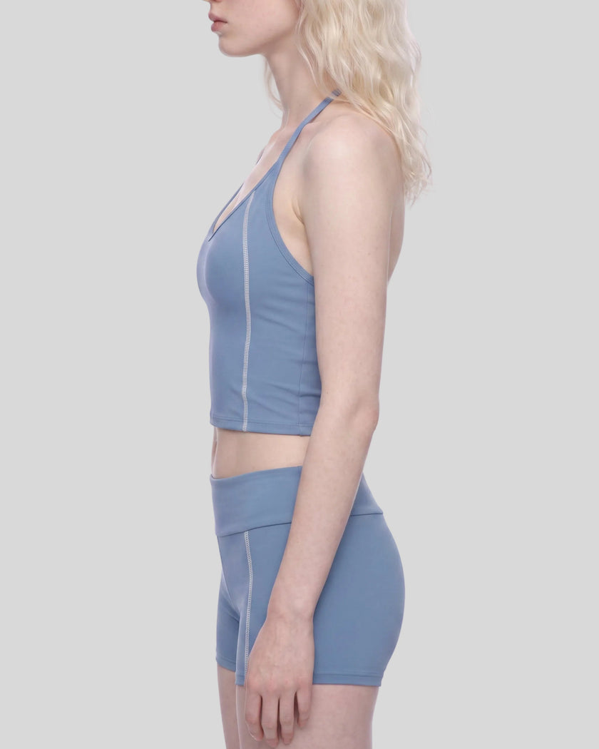 Mid body side view of woman wearing TrackLine Halter Yoga Top in blue