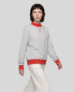 Model wearing the Athlesi TrackLine Heritage Sweatshirt in flower gray with red contrast trim, front view