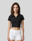Upper body front view of a woman wearing the Athlesi TrackLine Lapel Crop Top in black
