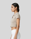 Side view of a woman wearing the Athlesi TrackLine Lapel Crop Top in light coffee