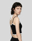 Back angle view of model wearing black and white TrackLine Lounge Halter Tank featuring open halter silhouette