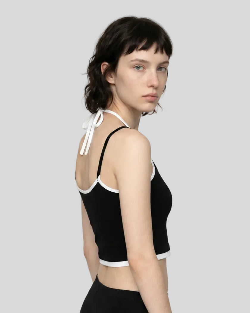 Back angle view of model wearing black and white TrackLine Lounge Halter Tank featuring open halter silhouette