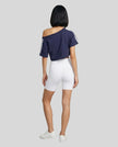 Full body back view of the Athlesi TrackLine Off-Shoulder Tee in blue in a clean modern architectural environment