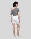 Full body back view of the Athlesi TrackLine Off-Shoulder Tee in gray in a clean modern architectural environment