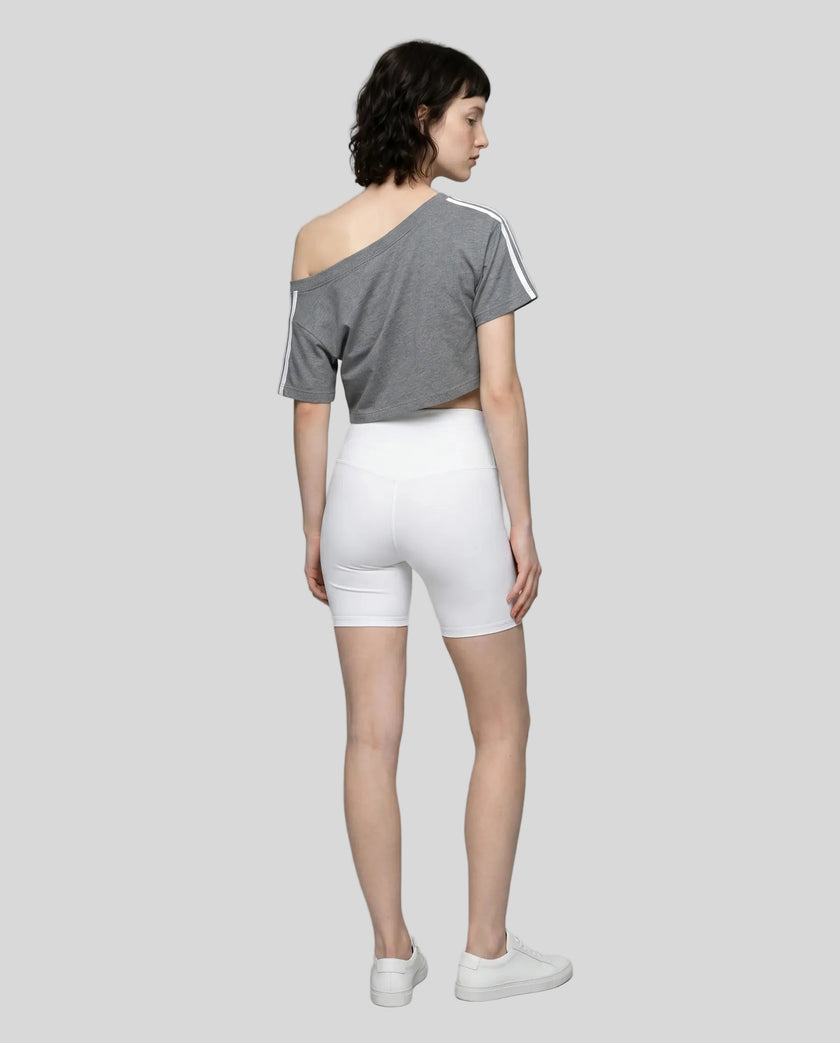 Full body back view of the Athlesi TrackLine Off-Shoulder Tee in gray in a clean modern architectural environment
