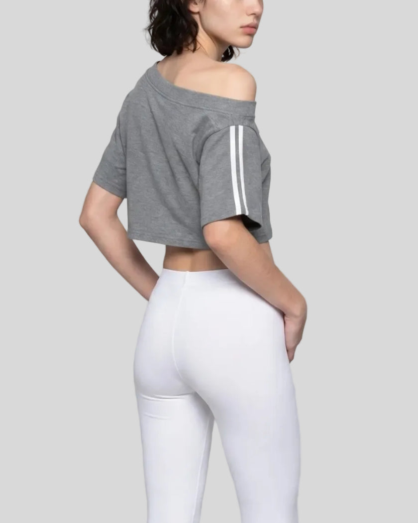 Back angled view of the Athlesi TrackLine Off-Shoulder Tee in gray styled with elevated athleisure pieces