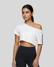 Upper body front view of a woman wearing the Athlesi TrackLine Off-Shoulder Tee in white