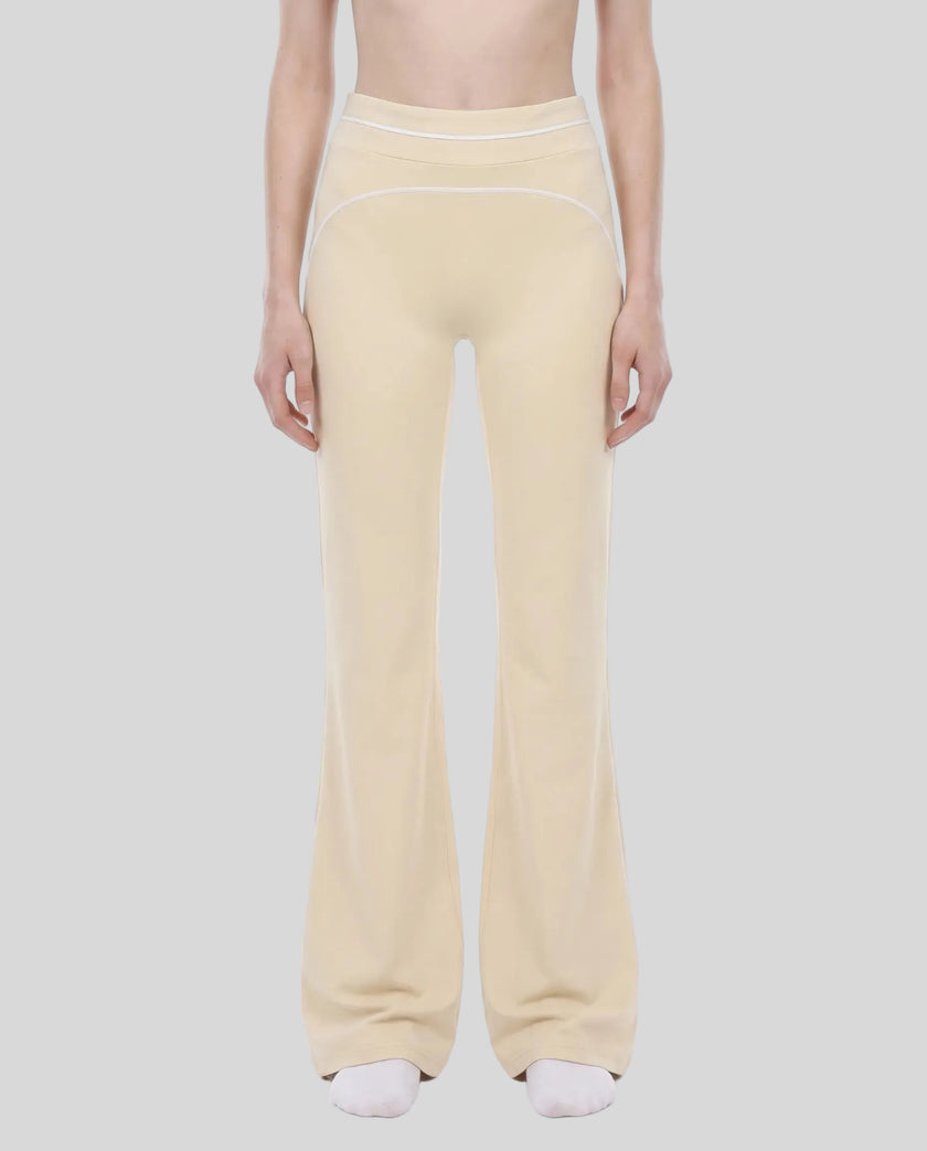 Model wearing the TrackLine Outline Flared Pants in Light Apricot viewed from the front