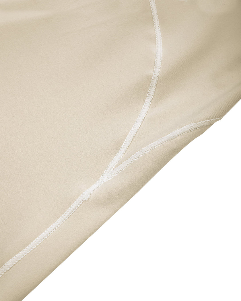 Side close-up of the TrackLine Outline Flared Pants in Light Apricot highlighting the contrast piping detail