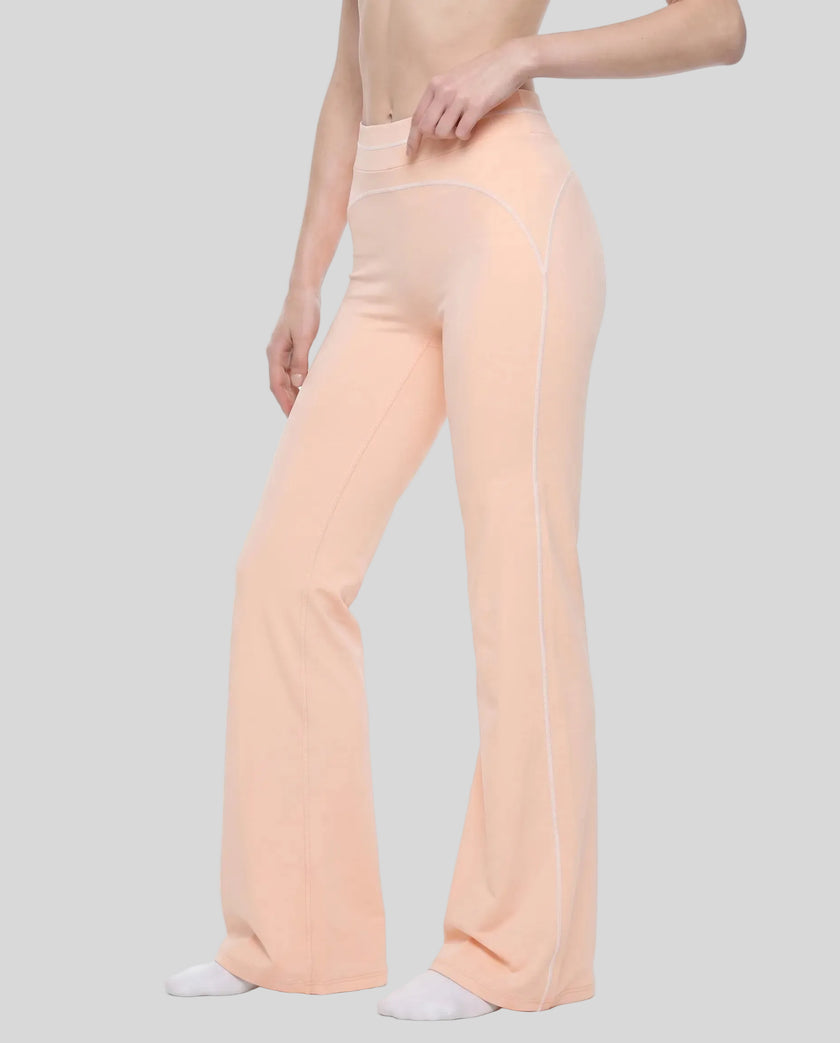 Front angled view of a model wearing the TrackLine Outline Flared Pants in Light Pink