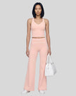 Front angled full body view of a model wearing the TrackLine Outline Flared Pants in Light Pink