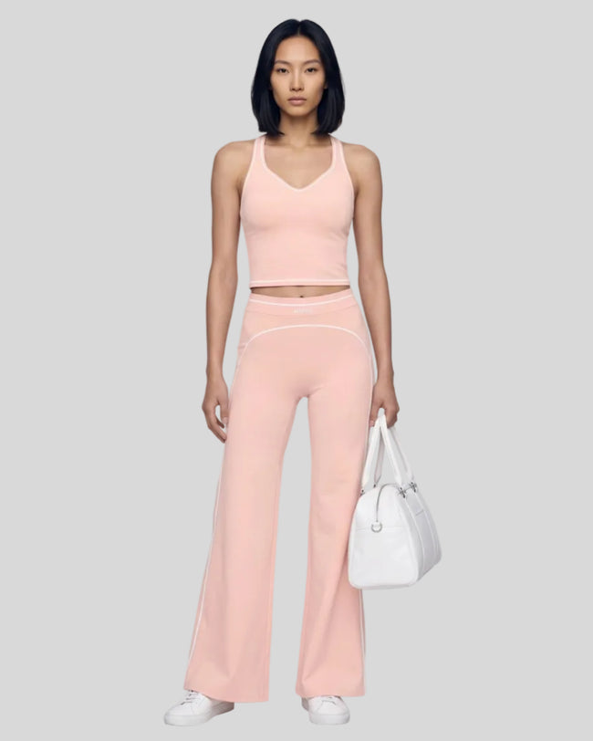 Front angled full body view of a model wearing the TrackLine Outline Flared Pants in Light Pink