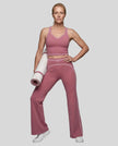 Front angled full body view of a model wearing the TrackLine Outline Flared Pants in Purple