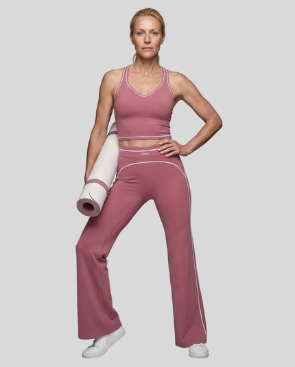 Front angled full body view of a model wearing the TrackLine Outline Flared Pants in Purple