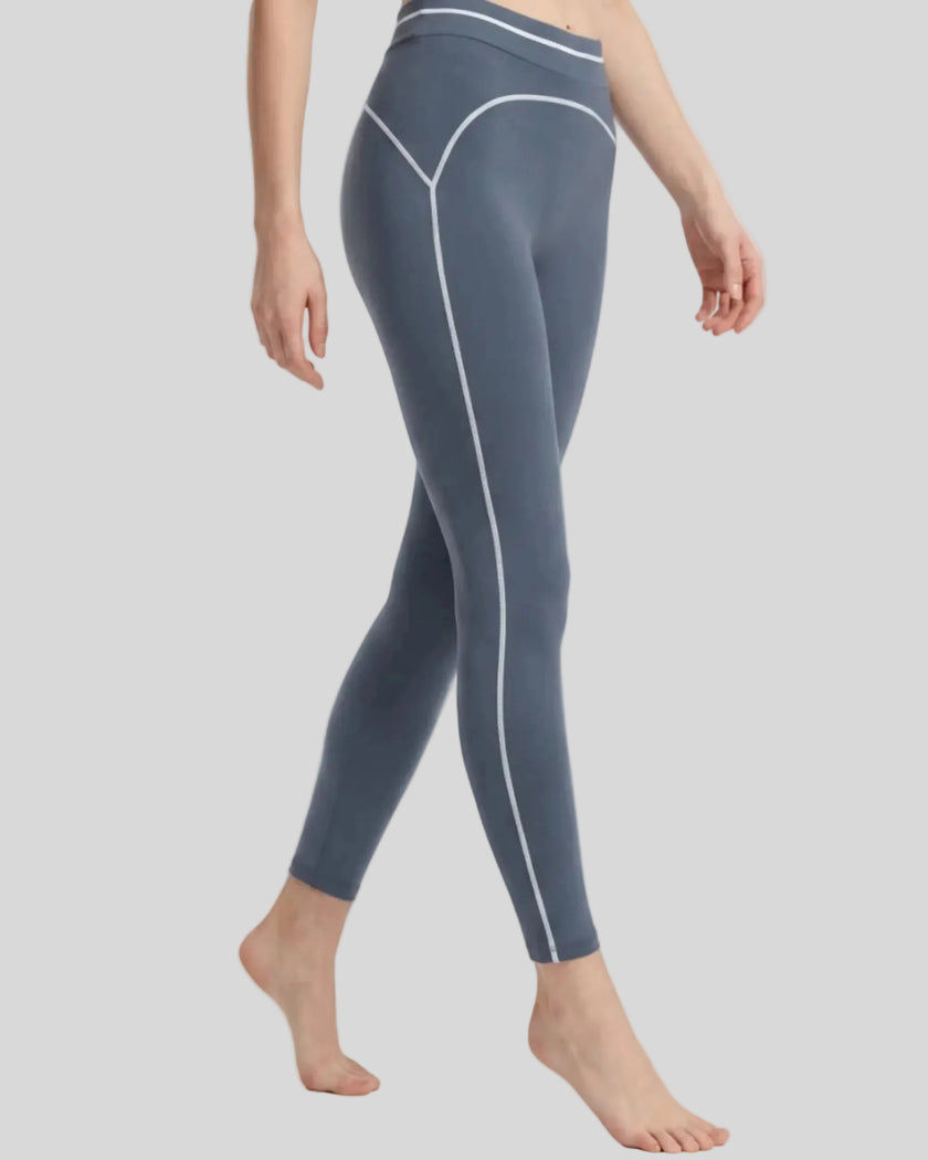 Side angled view of a model wearing the TrackLine Outline Leggings in Haze Blue