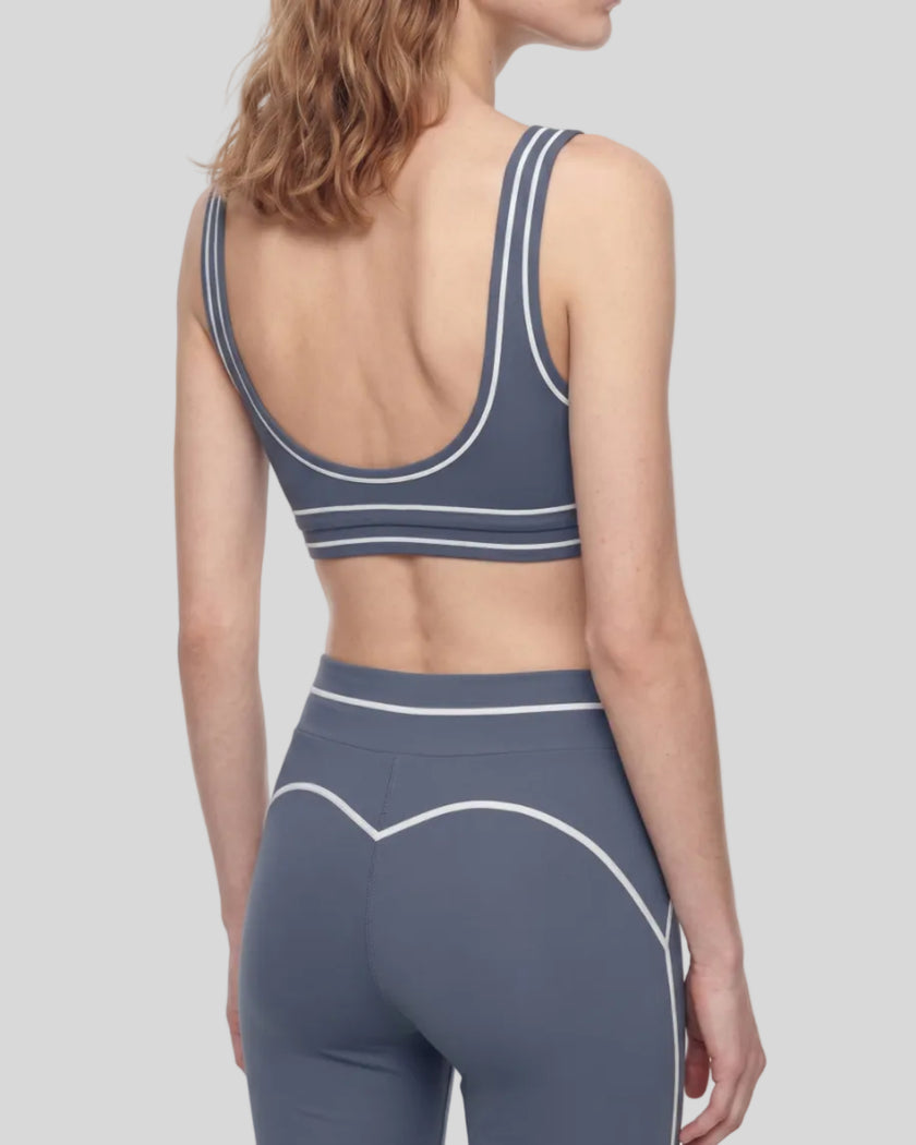 Back angled view of a model wearing the TrackLine Outline Sports Bra in Haze Blue