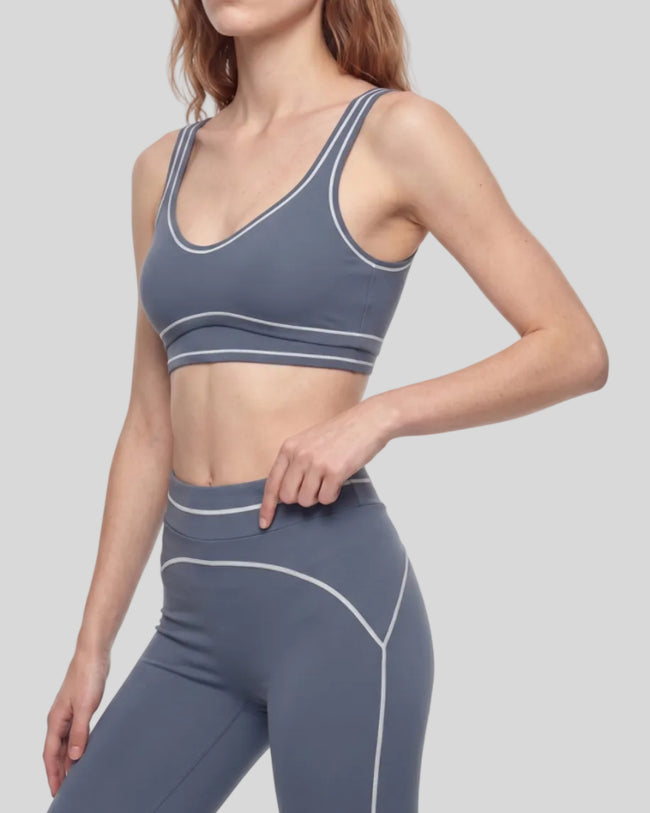 Front angled view of a model wearing the TrackLine Outline Sports Bra in Haze Blue