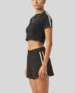 Side view of the Athlesi TrackLine Performance Crop Tee in black showing the fitted cropped silhouette