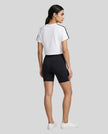 Full body back view of the Athlesi TrackLine Performance Crop Tee in white in a clean architectural setting