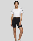 Full body front view of a woman wearing the Athlesi TrackLine Performance Crop Tee in white styled with modern athleisure pieces