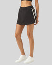 Angled lower body front view of the Athlesi TrackLine Performance Skort in black