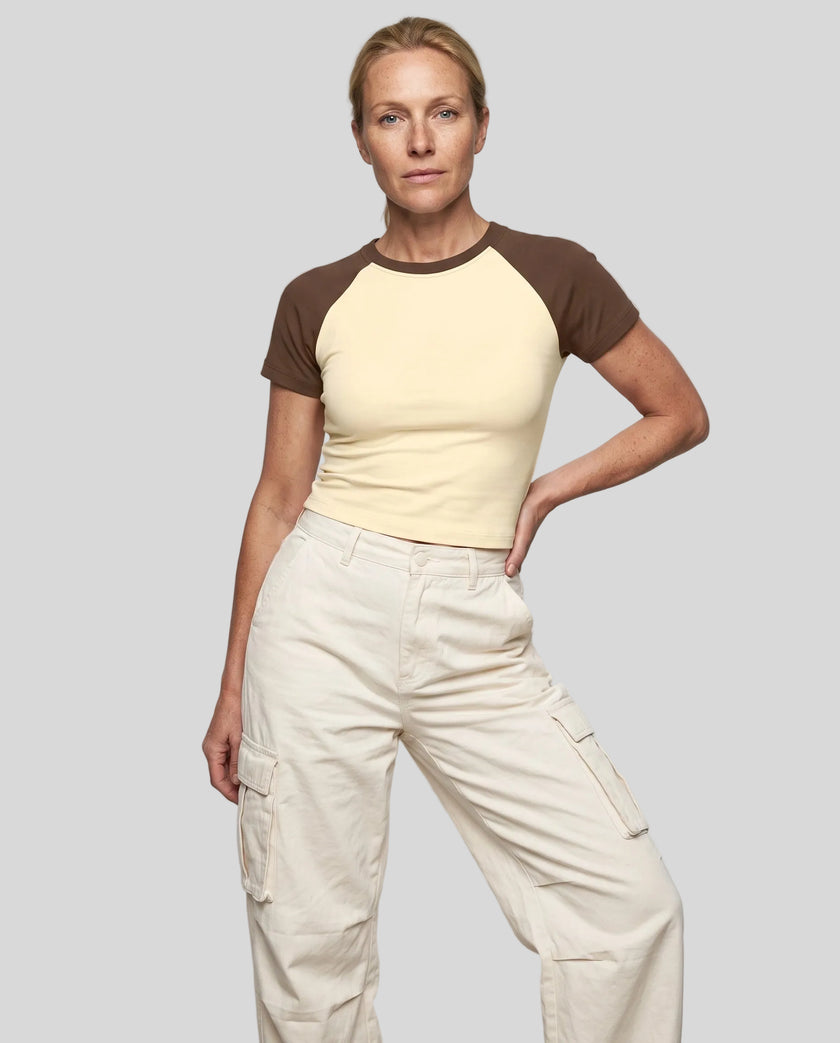 Woman wearing the TrackLine Raglan Baby Tee in Apricot with Coffee from the front showing its fitted cropped silhouette