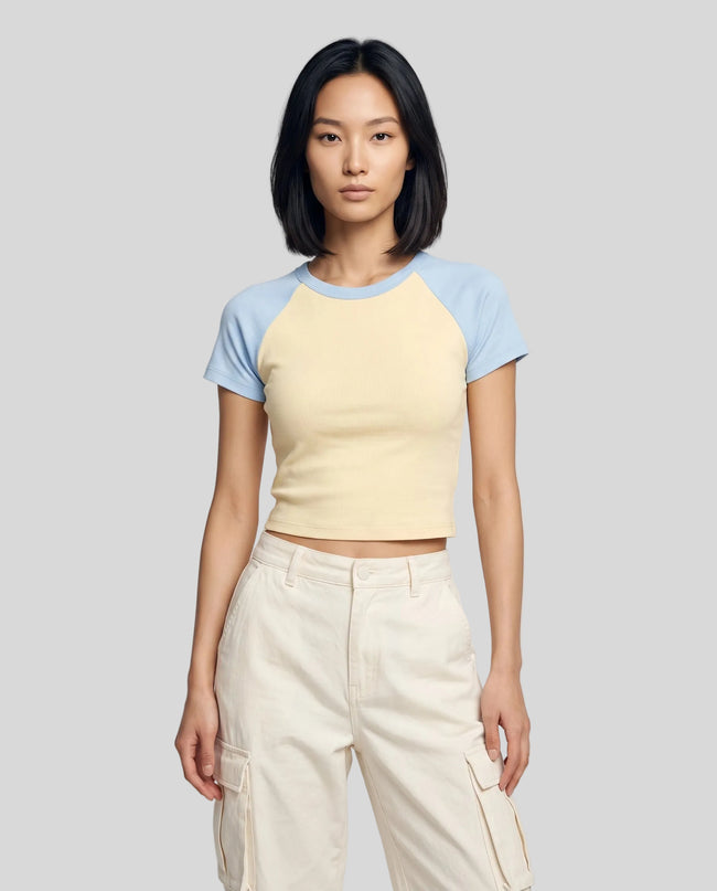 Woman wearing the TrackLine Raglan Baby Tee in Apricot with Sky Blue from the front showing its fitted cropped silhouette