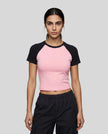 Woman wearing the TrackLine Raglan Baby Tee in Pink with Black from the front showing its fitted cropped silhouette