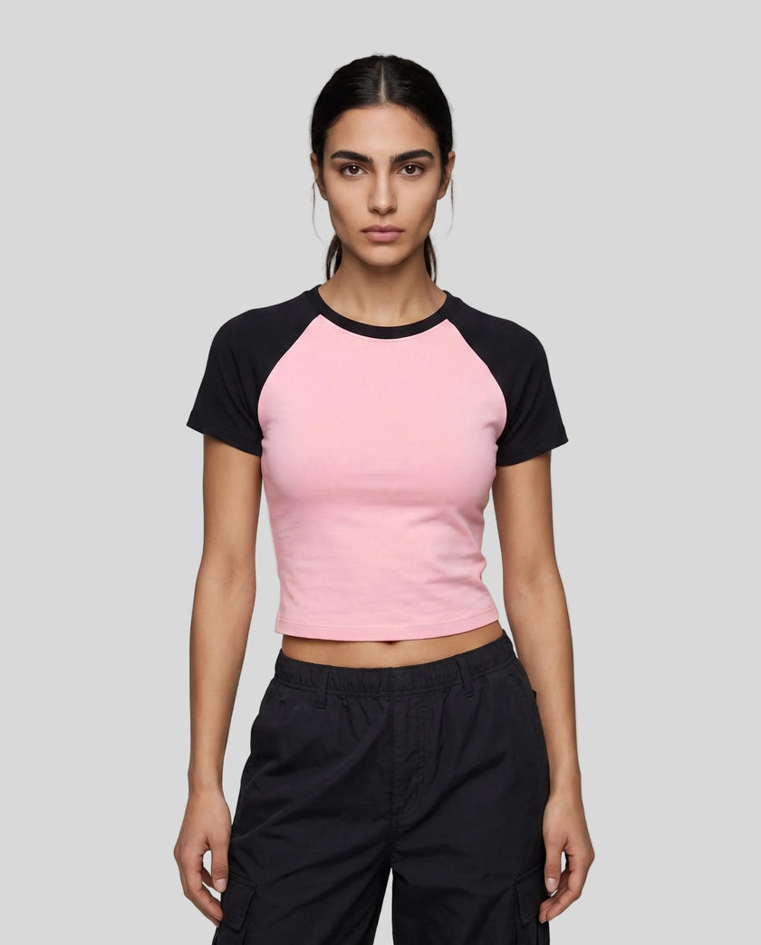 Woman wearing the TrackLine Raglan Baby Tee in Pink with Black from the front showing its fitted cropped silhouette