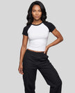 Woman wearing the TrackLine Raglan Baby Tee in White with Black from the front showing its fitted cropped silhouette