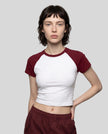 Woman wearing the TrackLine Raglan Baby Tee in White with Wine Red from the front showing its fitted cropped silhouette