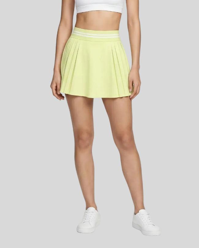 Woman wearing TrackLine Rally Skirt in light green front view with retro court-inspired styling
