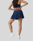 Angled back view of TrackLine Rally Skirt in navy blue styled for tennis, pickleball, and athleisure wear