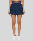 Woman wearing TrackLine Rally Skirt in navy blue front view with retro court-inspired styling