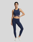 Full body front view of woman wearing a navy blue Trackline Rally Sports Bra with matching color leggings