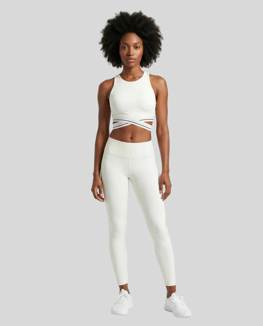 Full body front view of woman wearing a white Trackline Rally Sports Bra with matching color leggings