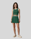 Front view of Model wearing the TrackLine Rally Tank in Blackish Green with White, paired with Trackline Rally Skirt in Blackish Green.